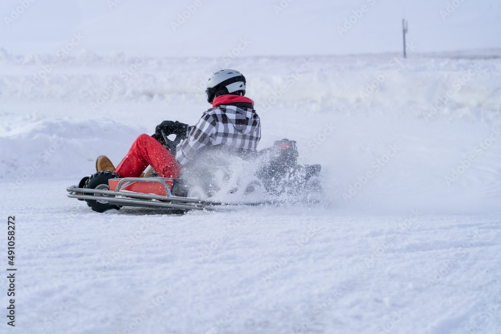 Go karting on icy track in winter. Adult kartng driver in action on outdoor icy track Go karting on icy track in winter. Adult kartng driver in action on outdoor icy track