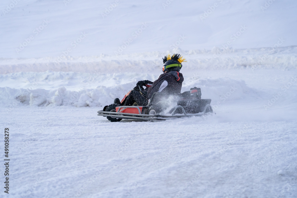 Go karting on icy track in winter. Adult karting driver in action on outdoor icy track - obrazy, fototapety, plakaty 
