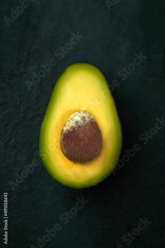 Avocado in a cut on a dark green background, super food, organic vegetables, ecological product