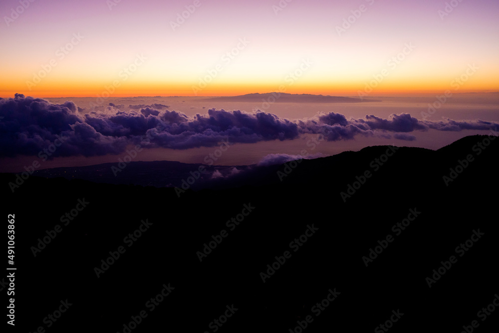 Sunset over the top of a mountain, over the clouds below, a mysterious atmosphere copy space.