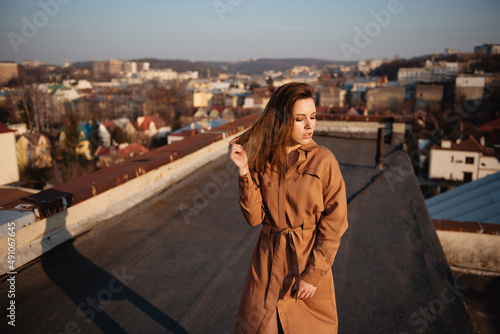 Young woman in dress posing on rooftop at sunset