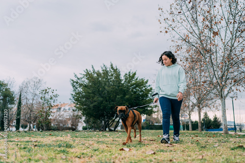 girl walks with her boxer dog through the public park © Juan Hernandez