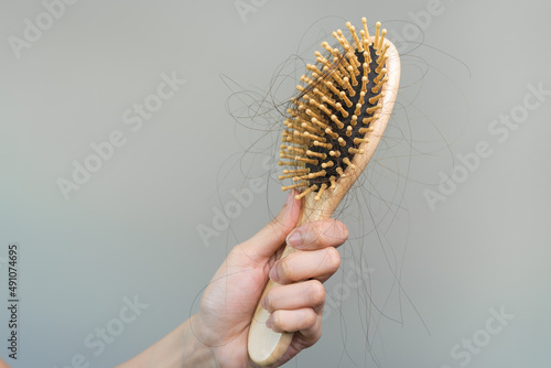 Hair fall problem concept. Shocked Asian woman looking at many hair lost in her hand and comb.