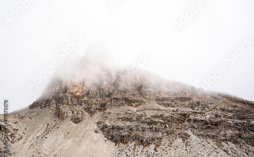 high altitude snow covered peak in the swiss alps with clouds and fog and steep alpine rock formation photo