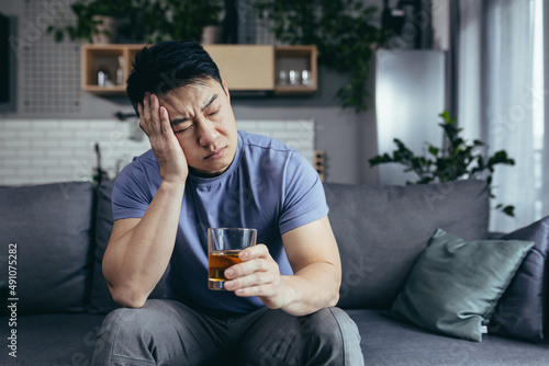 Konstfotografi Asian man at home alone, depressed drinking strong alcohol, single man