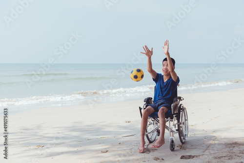 Young man with disability playing on the beach, Practice small muscle skills and large muscles skills through with sport outdoor activity in vacation, Natural therapy and mental health concept.