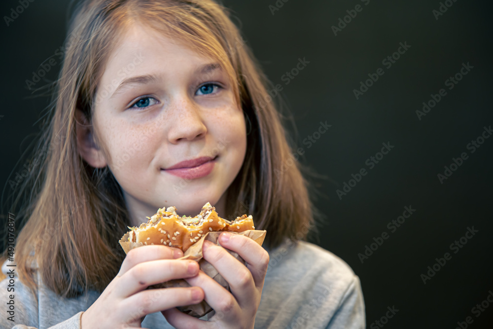 A little girl with freckles eats a burger. A little girl with freckles eats a burger.