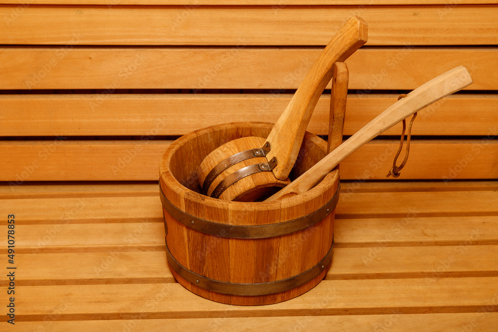 Wooden sauna bucket with spoon on bench