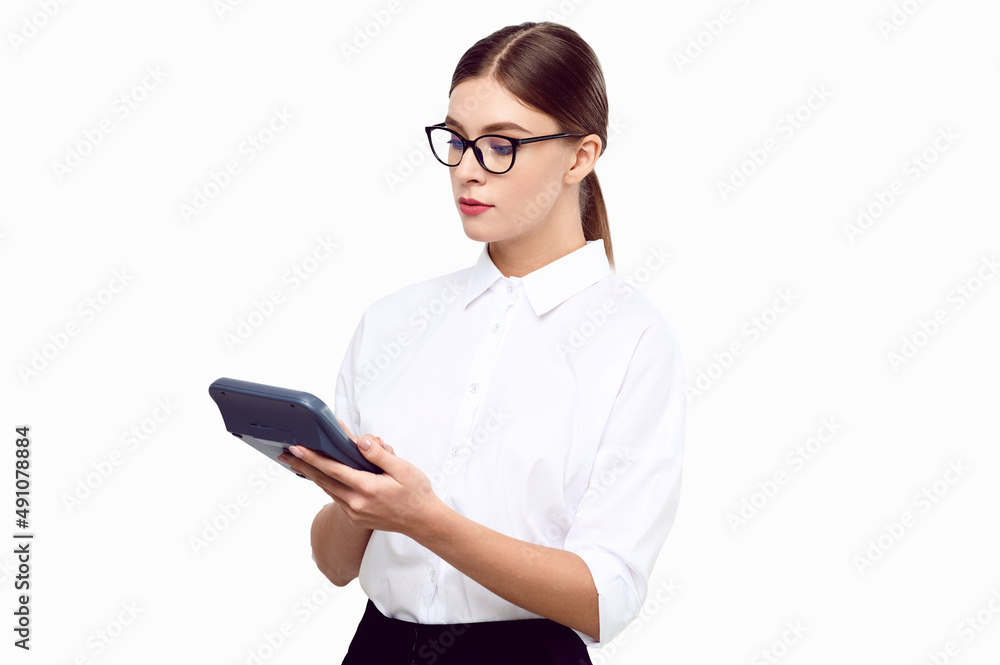 Young woman accountant with a calculator in her hands wearing white shirt glasses on a white isolated background. Business woman counting income