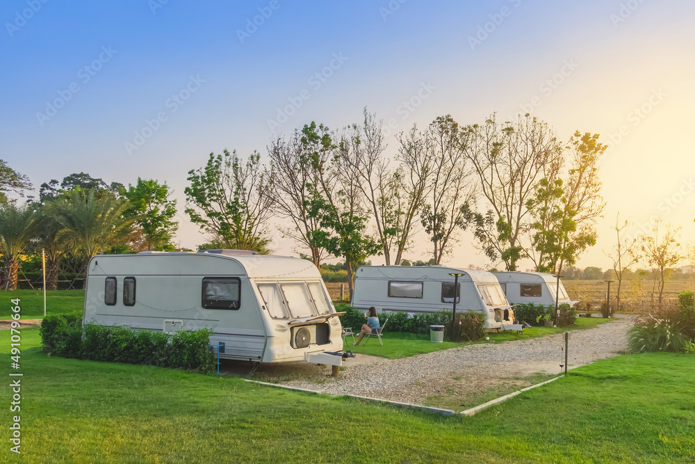 Cozy retro travel trailer Caravan on green grass before sunset near riverside in peaceful countryside. Family vacation travel RV, holiday trip in motorhome. Outdoor and Recreational Vehicles Theme. Cozy retro travel trailer Caravan on green grass before sunset near riverside in peaceful countryside. Family vacation travel RV, holiday trip in motorhome. Outdoor and Recreational Vehicles Theme.