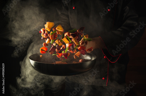 фотографія Chef prepares food in a hot pan with steam on a black background