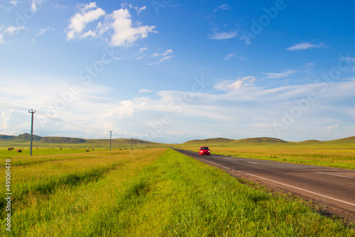Country paved road among hills and mown green fields. Summer landscape in sunny day at Khakassia, Russia