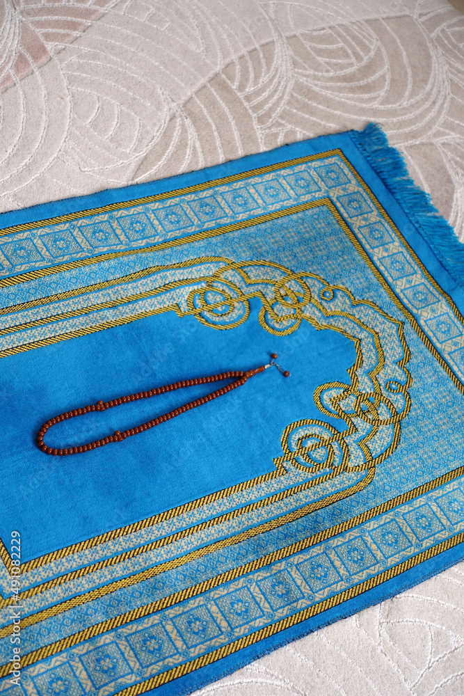 A blue, prayer rug, in the house, of a Muslim, his rosary, next to it, a prayer, rug, for worship in Islam, A blue, prayer rug, in the house, of a Muslim, his rosary, next to it, a prayer, rug, for worship in Islam,