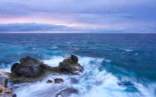 sunrise at punta sur isla mujeres, dramatic purple and blue sky with intense waves breaking on the rocks , fine art photography, long exposure