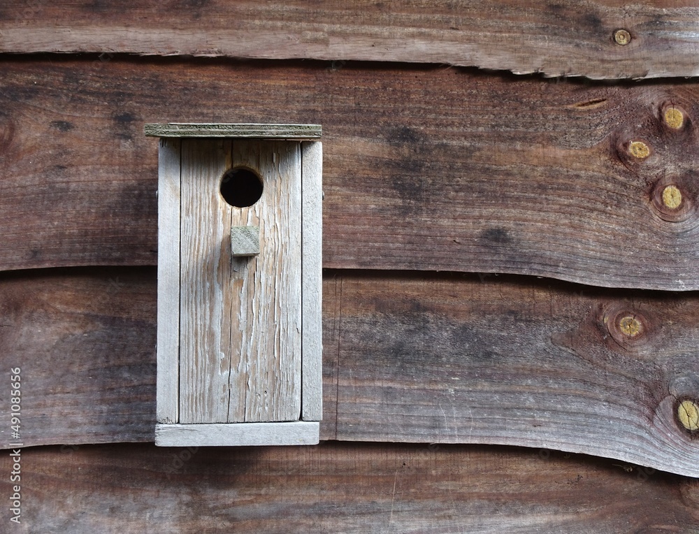 Wooden birdhouse against a wooden background.