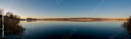 Panorama of autumn lake. Mirror reflection in water  blue sky.