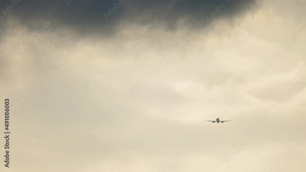 Jet airplane approaching to land in cloudy sky. Long shot, a passenger airliner descending before landing Jet airplane approaching to land in cloudy sky. Long shot, a passenger airliner descending before landing