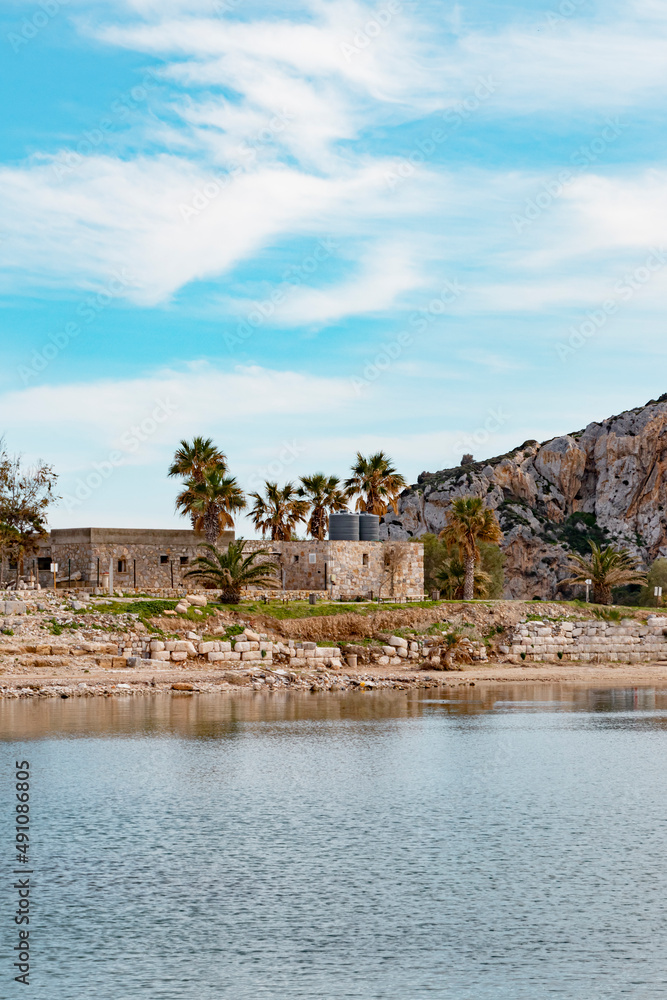 Stone wall hotel is surrounded by palm trees. It is located by sea. It has lots of windows. Medieval architecture. Vintage look real estate in Turkey. Stone wall hotel is surrounded by palm trees. It is located by sea. It has lots of windows. Medieval architecture. Vintage look real estate in Turkey.