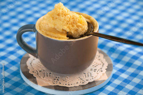 cake in a mug. dessert. Vanilla dessert cooked in the microwave. cake mug. Easy, fast to cook.vanilla biscuit in a spoon . Close-up of banana flavored mugcake. homemade cupcake recipe. breakfast. photo