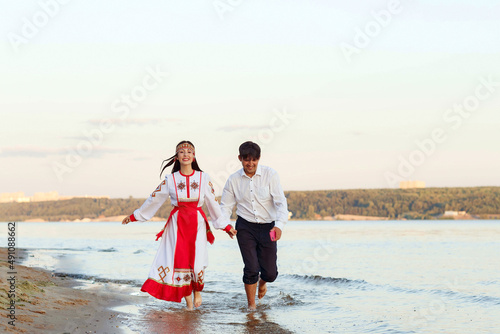 a girl in national Chuvash clothes and her boyfriend on the river bank photo