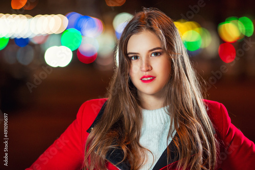Beautiful young brown haired girl in night city lights with very attractive colorful blurred background