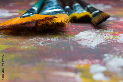 Paint brushes on a colorful background in the studio.