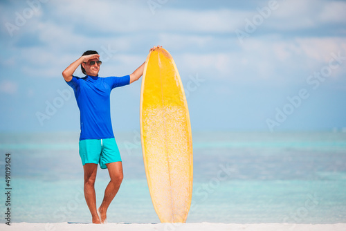Young surf man at white beach with yellow surfboard