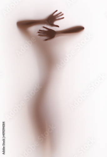 Diffuse silhouette of a pretty woman body with arms, hands and fingers, behind a textile surface. Cut out, separated, white background abstract image.