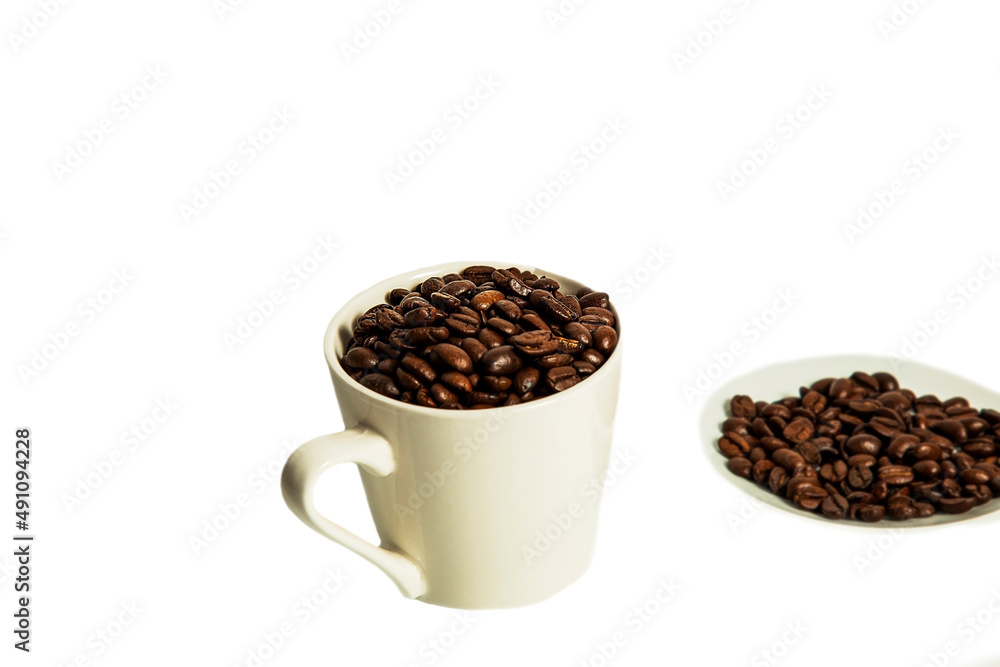 Coffee beans lie in a white mug and saucer on a white background. Isolate. Coffee beans lie in a white mug and saucer on a white background. Isolate.