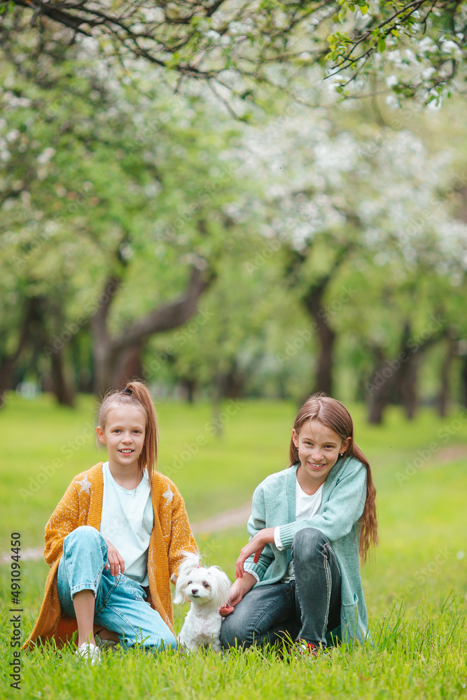 Little smiling girls playing and hugging puppy in the park Little smiling girls playing and hugging puppy in the park