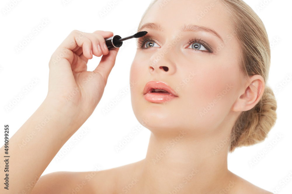 Accentuating her eyelashes. A gorgeous young woman applying mascara while isolated on white.