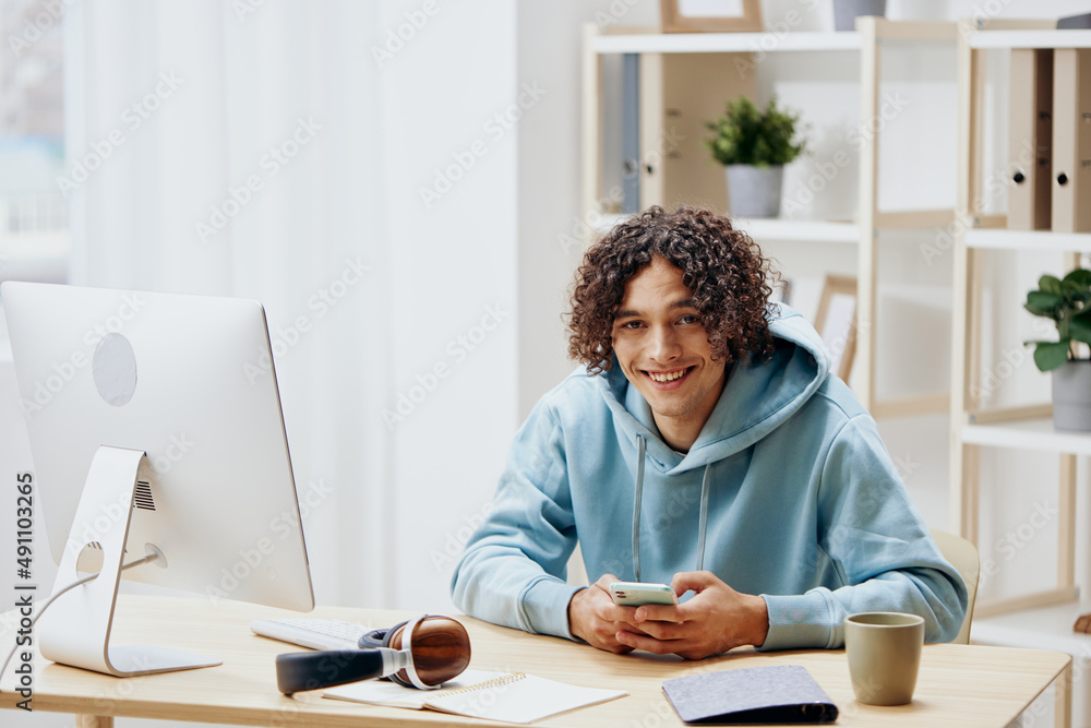 handsome guy in a blue jacket in front of a computer with phone technologies handsome guy in a blue jacket in front of a computer with phone technologies