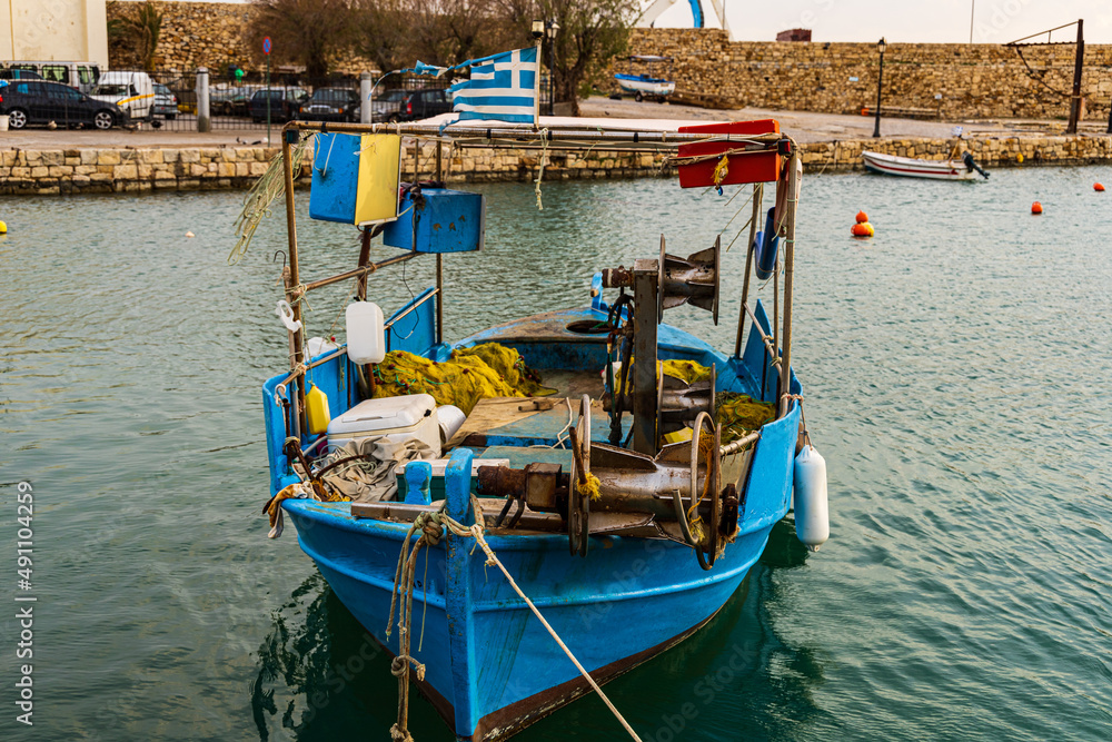 Fototapeta premium Scenic shot of a calm fisher boat with a scenic sunrise at the greek harbor of Rethymno old town in Crete, Greece