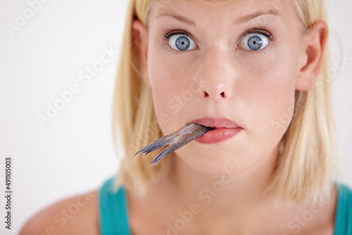 The taste of this fish is surprising. Portrait of a young woman eating a whole fish. photo