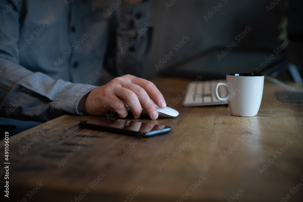 Gros plan sur la main d'un employé de bureau qui travaille sur un ordinateur. Vue sur la main qui tient la souris. On aperçoit une tasse de café, un téléphone et le clavier de l'ordinateur Gros plan sur la main d'un employé de bureau qui travaille sur un ordinateur. Vue sur la main qui tient la souris. On aperçoit une tasse de café, un téléphone et le clavier de l'ordinateur