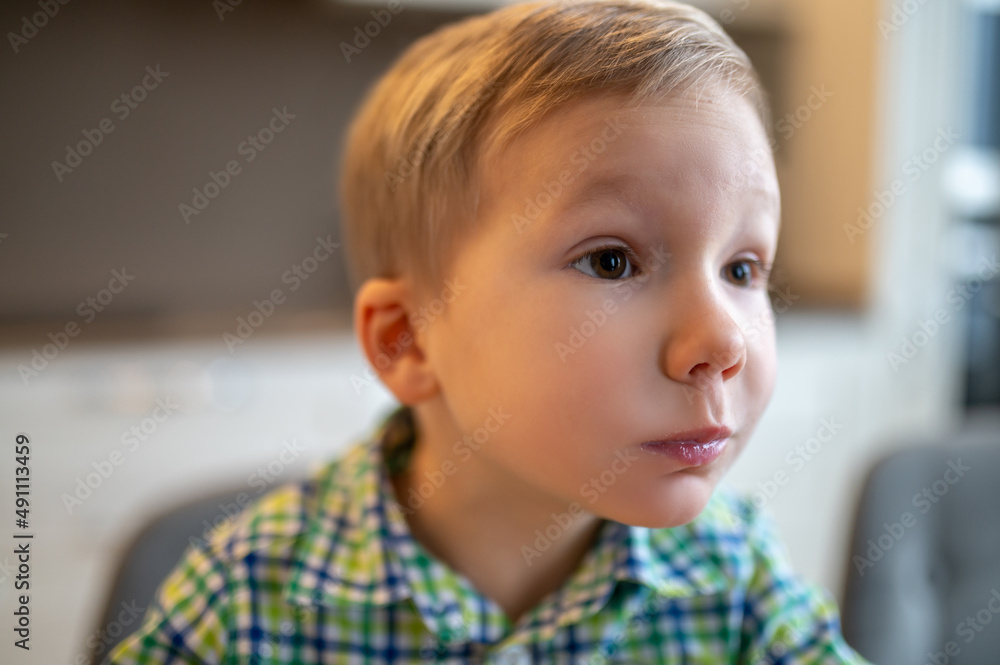 Surprised boy seated with his mouth full looking at something