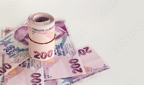 Two Hundred Turkish Banknotes rolled up on paper money at white surface with copy space