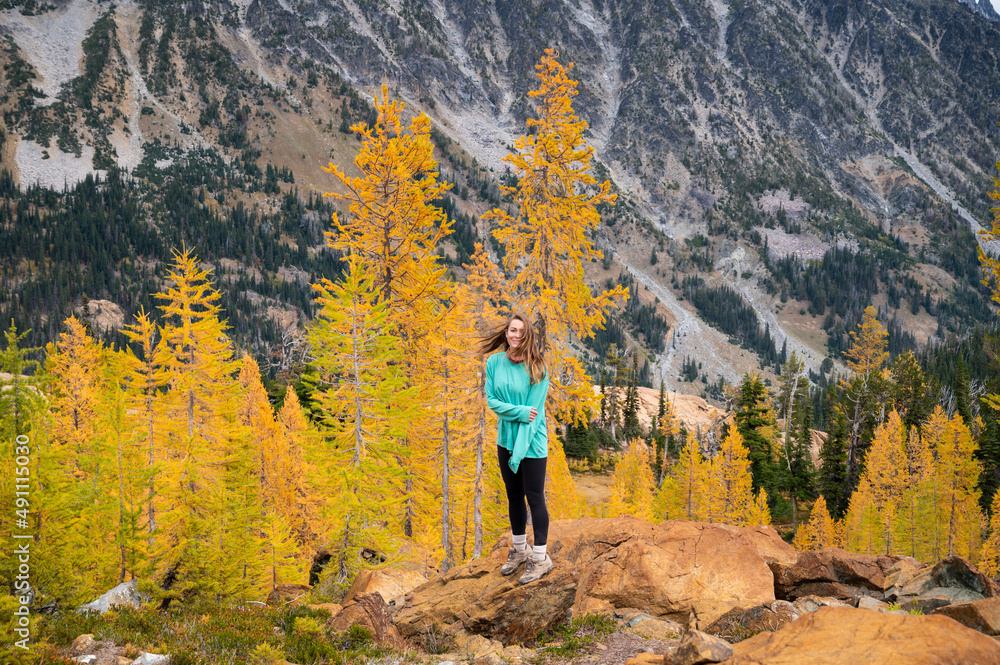 Fit female posing in a forest of golden larches in the fall
