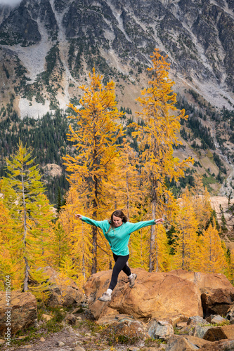 Fit female hiking in a forest of golden larches in the fall