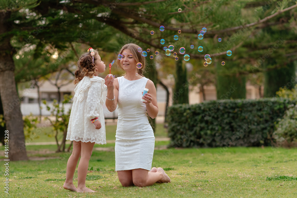mother and daughter blow soap bubbles outdoors mother and daughter blow soap bubbles outdoors