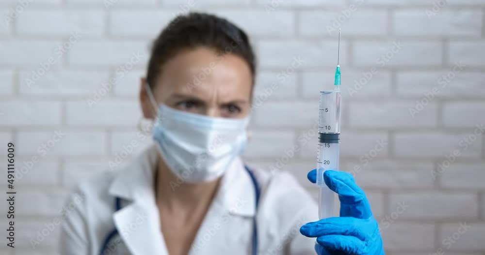 Laboratory doctor with full syringe. A view of laboratory doctor hold and examine a syringe with vaccine in her hand. Laboratory doctor with full syringe. A view of laboratory doctor hold and examine a syringe with vaccine in her hand.