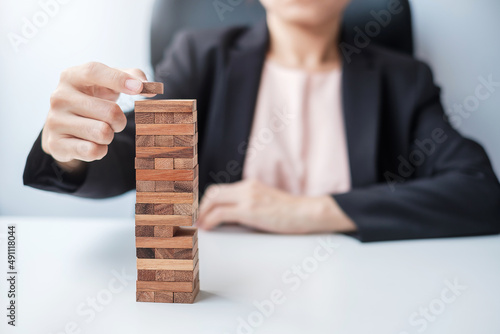 Businesswoman hand placing or pulling wooden block on the tower. Business planning, Risk Management, Solution and strategy Concepts