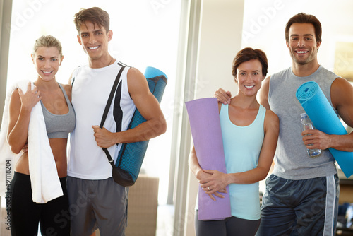 Part of a fitness team. Portrait of four young adults smiling at the camera with their yoga gear.
