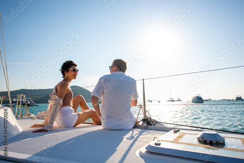 Caucasian couple enjoy outdoor luxury party drinking champagne with talking together while catamaran boat sailing at sunset. Man and woman relax with outdoor lifestyle on summer travel vacation © CandyRetriever 