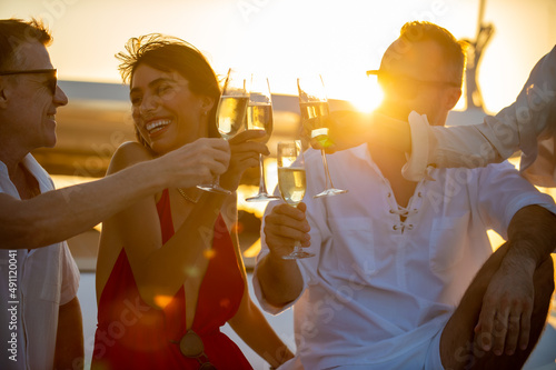 Photography Blurred Group of People man and woman friends enjoy party drinking champagne together while catamaran boat sailing at summer sunset