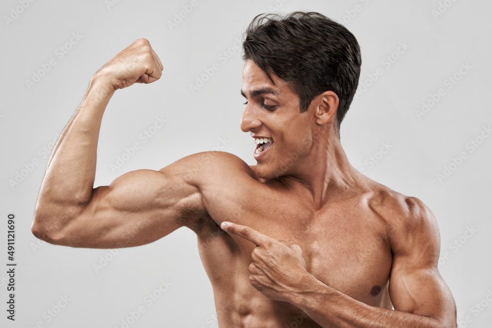 Boom. An isolated shot of a macho and muscular man pulling his bicep to show off. Boom. An isolated shot of a macho and muscular man pulling his bicep to show off.