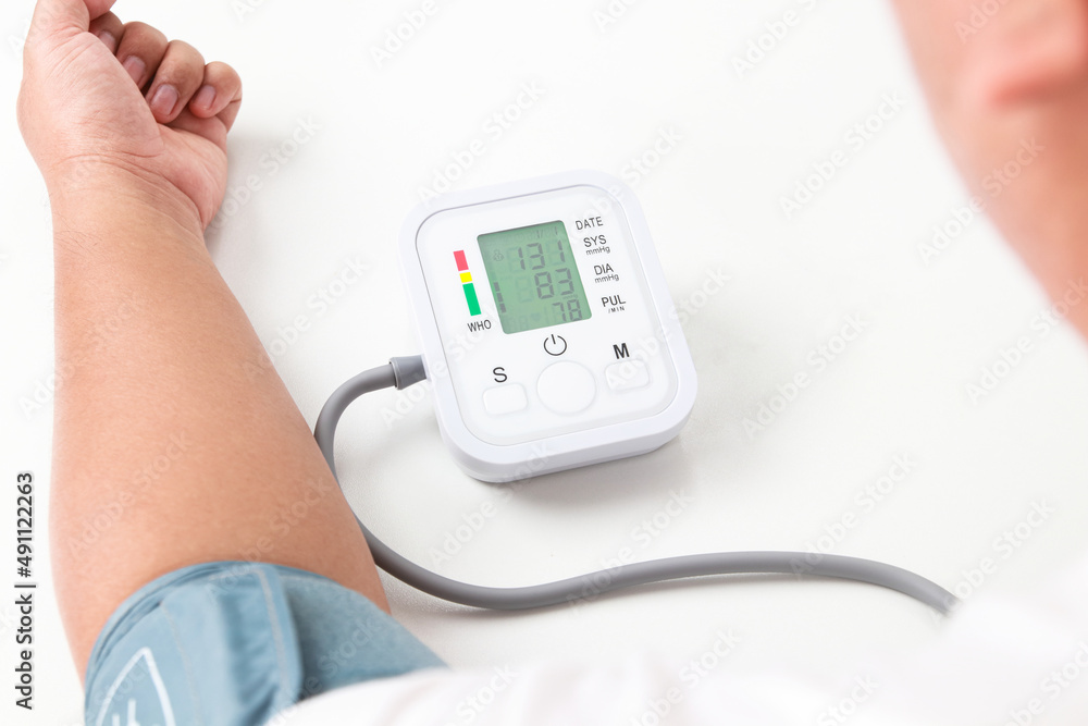 An obese man uses a blood pressure monitor on his arm himself. obesity concept The risk of high blood pressure, diabetes, high blood lipids coronary heart disease. health care An obese man uses a blood pressure monitor on his arm himself. obesity concept The risk of high blood pressure, diabetes, high blood lipids coronary heart disease. health care