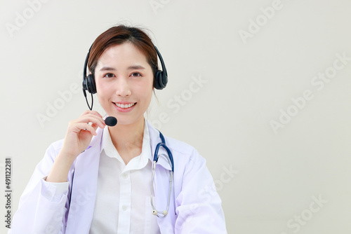 Asian female doctor smiling beautifully Providing treatment services for patients with online conversations via the Internet on laptop computers. online doctor concept. Copy space