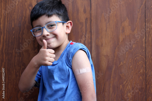 Konstfotografi Little 6-year-old Latino boy with glasses and a blue shirt shows his arm with a