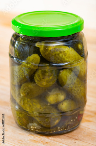 Pickled cucumbers with spices in glass jar on a wooden surface. High quality photo